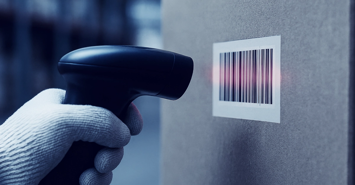 Warehouse-Barcoding_A-How-To-Guide-for-Ecommerce-Brands Warehouse worker scans a barcode on a parcel using a handheld barcode scanner